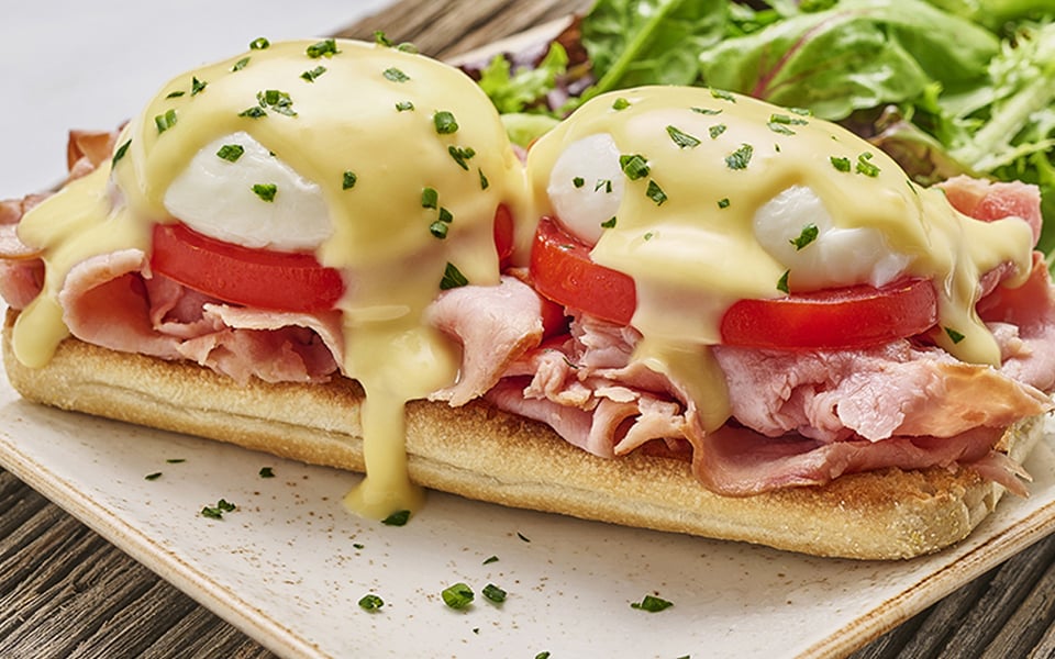 Two poached cage-free eggs atop toasted ciabatta piled high with smoked ham and vine-ripened tomato and covered with hollandaise. Served with lemon-dressed organic mixed greens.