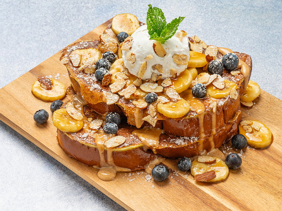 Thick-cut, custard-dipped, griddled challah bread topped with a drizzle of almond butter crème anglaise, caramelized bananas, fresh blueberries, whipped cream, honey roasted almonds, Maldon sea salt and mint. Lightly dusted with powdered cinnamon sugar.