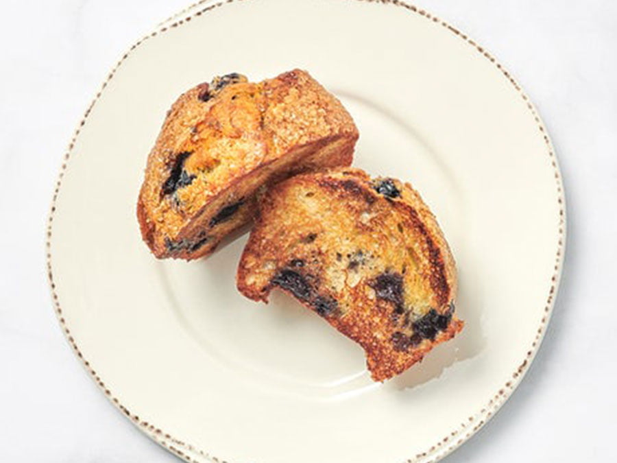 A small blueberry muffin with a sprinkle of powdered sugar on a white plate.