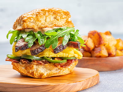A griddled, house-baked buttermilk biscuit with sliced brisket, hardwood smoked bacon, folded cage-free eggs, melted sharp Cheddar, chipotle aioli, house-pickled jalapeños and lemon-dressed arugula. Served with a side of freshly seasoned potatoes.