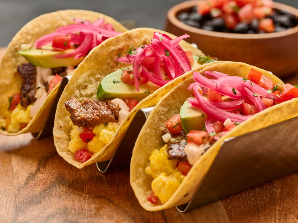 Three wheat-corn tortillas with seasoned carne asada, scrambled cage-free eggs, Cheddar and Monterey Jack, housemade pico de gallo, fresh sliced avocado, house-pickled red onions, cilantro and Valentina Hot Sauce crema. Served with a side of seasoned black beans.
