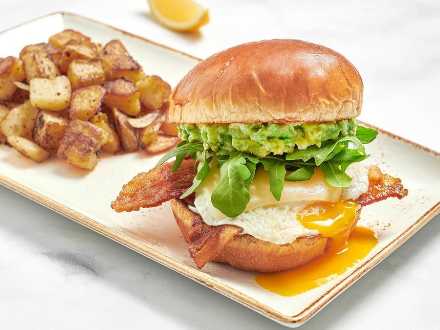 Bacon, an over-easy cage-free egg, Gruyere cheese, fresh smashed avocado, mayo and lemon-dressed arugula on a brioche bun with a side of fresh, seasoned potatoes.