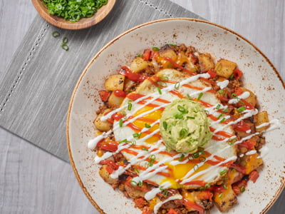 Chorizo, red bell pepper and potato hash topped with two cage-free eggs any style, Cheddar and Monterey Jack, spicy ketchup, lime crema drizzle, fresh smashed avocado and scallions.