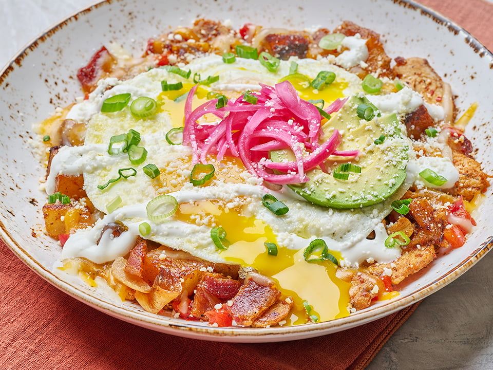Honey chipotle glazed all-natural chicken, hardwood smoked bacon, diced red bell peppers, house-roasted onions, Cheddar and Monterey Jack in a potato hash, topped with two cage-free eggs any style, Cotija cheese, house-pickled red onions, fresh avocado, lime crema and scallions.