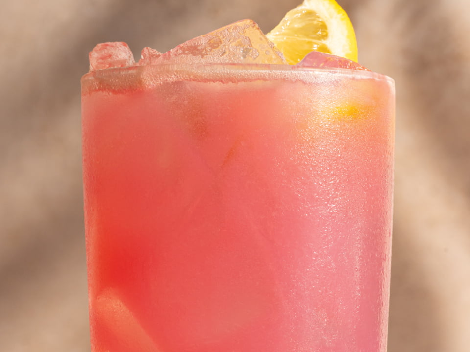 A vibrant, exotic tropical beverage, features bright pink or purple hues, served cold in a glass.