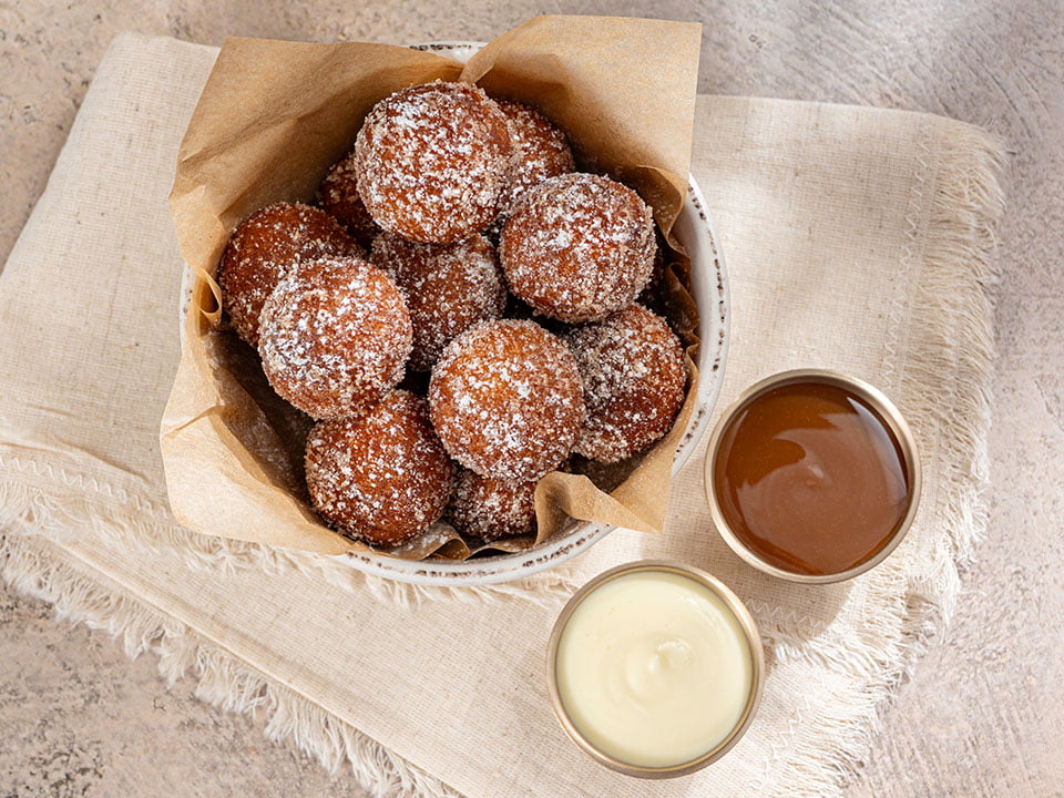 Warm cake donut holes tossed with pumpkin spiced sugar and lightly dusted with powdered cinnamon sugar. Served with salted caramel and crème anglaise for dipping.