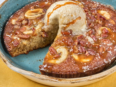 House-baked banana bread with fresh sliced bananas and pecans, topped with brown sugar butter, a drizzle of salted caramel and powdered cinnamon sugar.