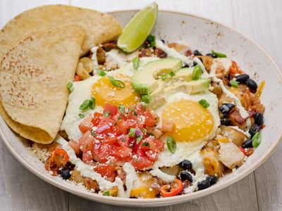 Hardwood smoked bacon, sliced grilled chicken and house-pickled sweet peppers in a potato hash, topped with two cage-free eggs any style, seasoned black beans, Cheddar and Monterey Jack, fresh avocado, housemade pico de gallo, Cotija cheese, scallions and a drizzle of jalapeno crema. Served with two warm wheat-corn tortillas.