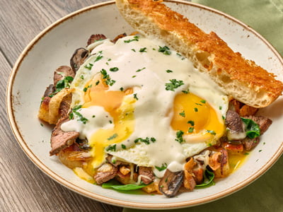 Seared steak, house-roasted Crimini mushrooms and onions, Mozzarella and fresh spinach in a potato hash. Topped with two cage-free eggs any style, Parmesan cream sauce and fresh herbs. Served with Parmesan-crusted ciabatta.