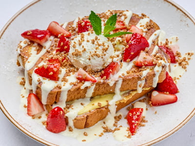 Thick-cut, custard-dipped challah bread layered with lemon curd and topped with macerated strawberries, crème anglaise, lemon whipped cream, spiced gingerbread cookie crumbles and mint. Lightly dusted with powdered cinnamon sugar.