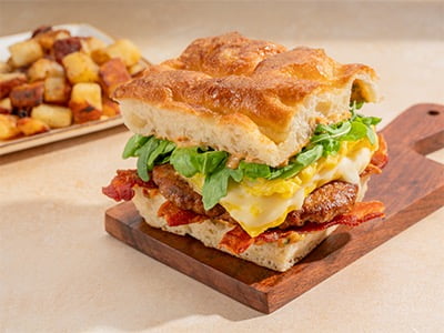 Hardwood-smoked bacon and a griddled Polidori Italian sausage patty, folded cage-free eggs, Mozzarella, Tuscan tomato aioli and lemon-dressed arugula served on toasted sea salt focaccia. Served with fresh, seasoned potatoes.