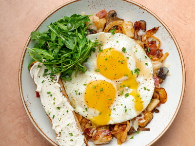 Creamy brie, Monterey Jack, diced hardwood smoked bacon, house-roasted onionsand Crimini mushrooms in a potato hash. Topped with two cage-free eggs any style,lemon-dressed arugula, freshly cracked black pepper, a drizzle of truffle honey andfresh herbs. Served with brie ciabatta toast.