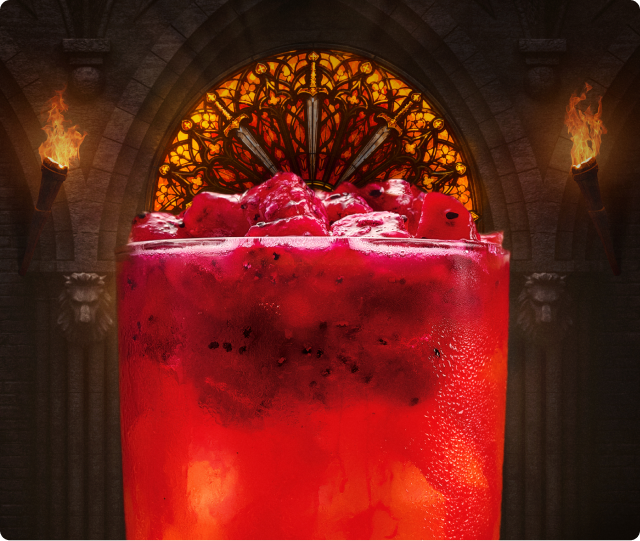 A glowing red cocktail in a candlelit, castle-like great hall